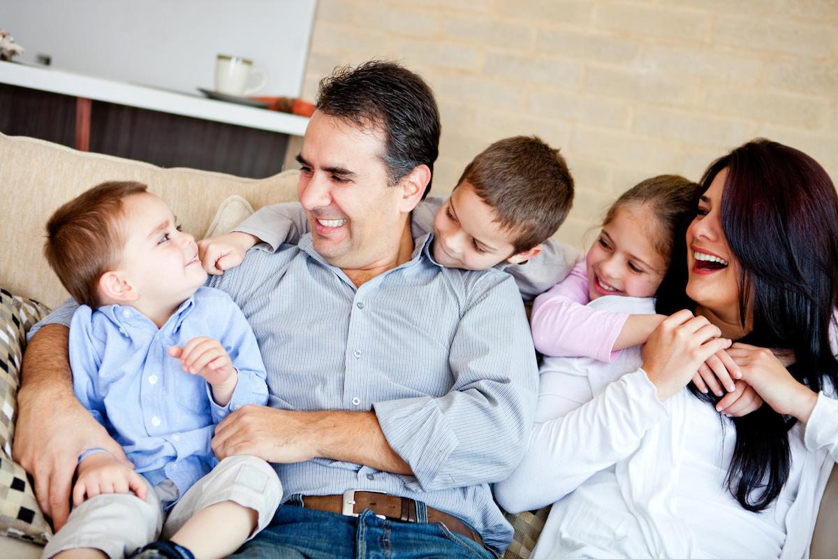 Happy family sitting on a couch laughing with each other