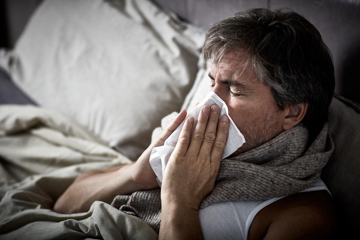 Man with cold blowing nose into a tissue Man with cold blowing nose into a tissue